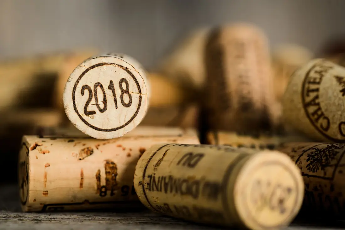 Des bouchons de liège posés sur une table, l’un d’eux porte le millésime 2018